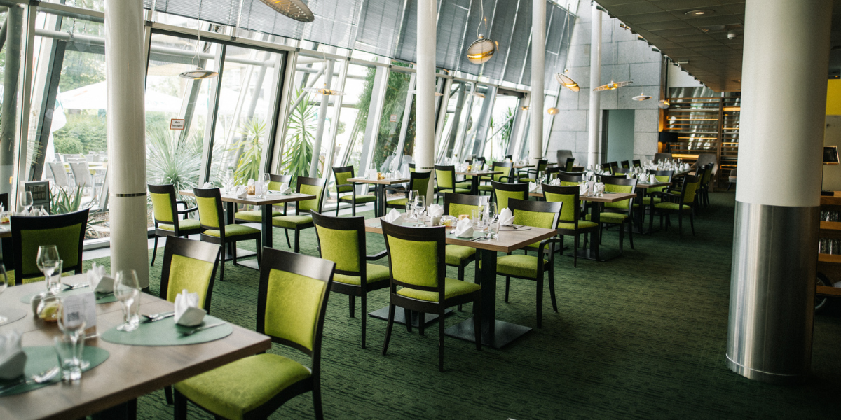 Restaurant Lemon, Tische mit Gläsern und Servietten, grüne Stühle, Panoramafenster