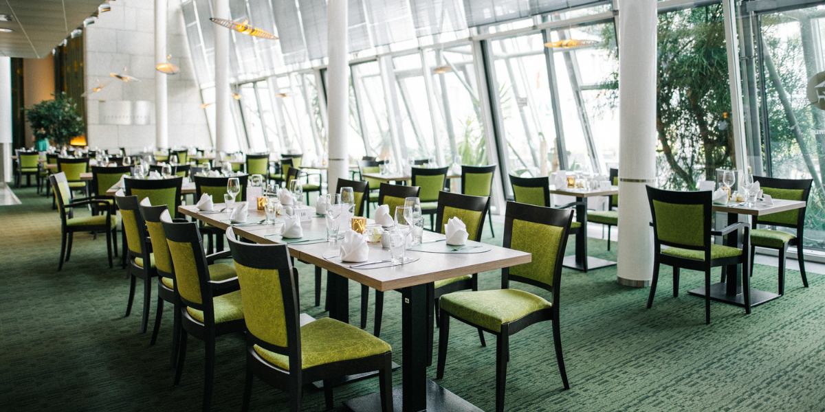 Restaurant Lemon, Tische mit Gläsern und Servietten, grüne Stühle, Panoramafenster