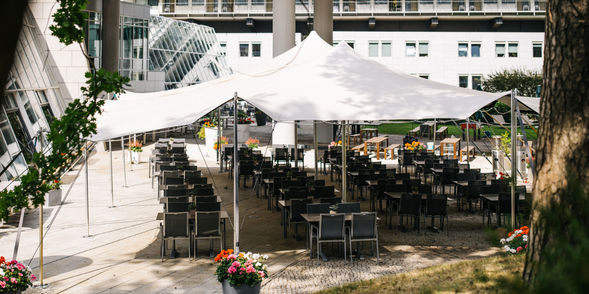 Restaurant Zeppelin, Terrasse, Großer Schirm, Tische mit Stühlen, Blumen